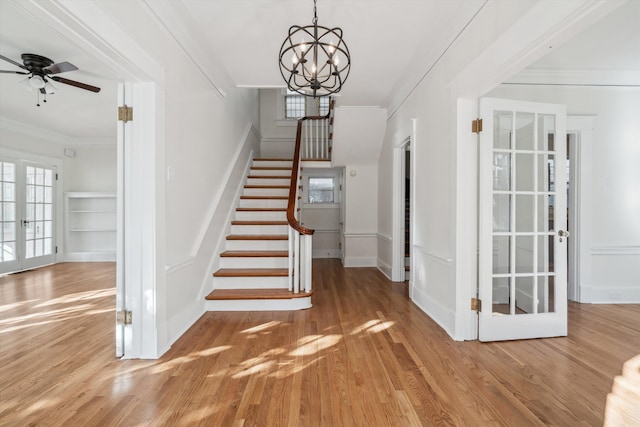 stairs with hardwood / wood-style floors, ceiling fan with notable chandelier, crown molding, and french doors