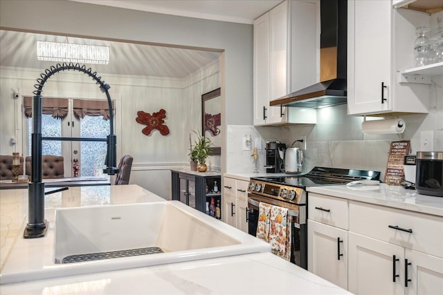 kitchen with white cabinets, wall chimney exhaust hood, stainless steel range with electric cooktop, and decorative backsplash