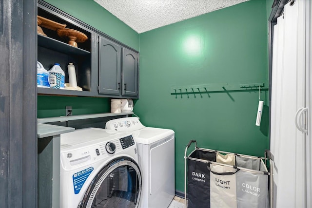 clothes washing area featuring washing machine and dryer, cabinets, and a textured ceiling