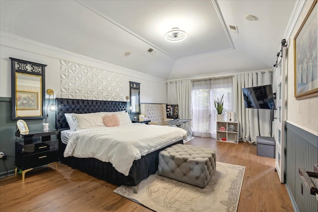 bedroom with wood-type flooring, crown molding, and lofted ceiling