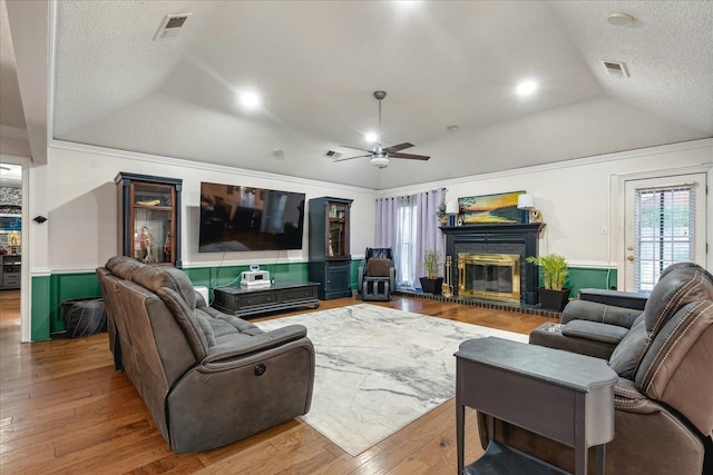 living room featuring lofted ceiling, a textured ceiling, hardwood / wood-style flooring, ornamental molding, and ceiling fan