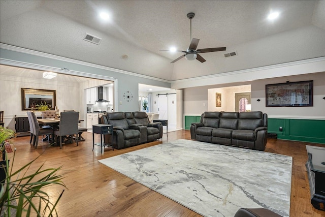 living room featuring lofted ceiling, a textured ceiling, ceiling fan, and crown molding