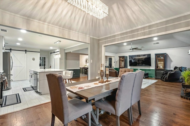 dining room featuring light hardwood / wood-style flooring, a barn door, ceiling fan, and sink