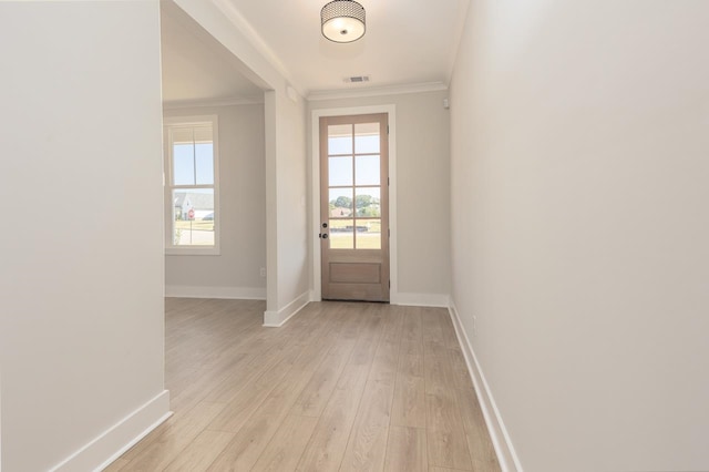 doorway to outside with a wealth of natural light, crown molding, and light wood-type flooring