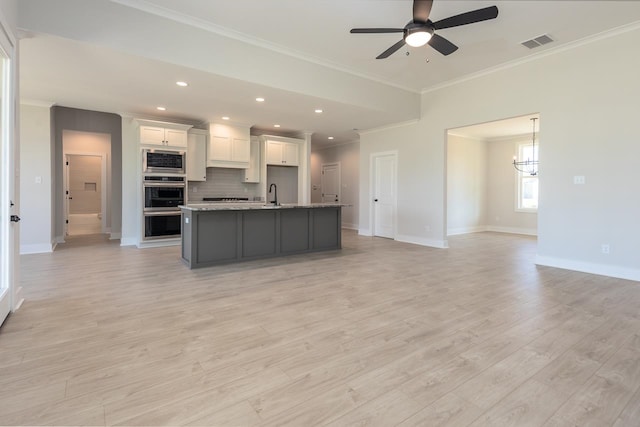 kitchen with ornamental molding, white cabinets, a kitchen island with sink, light hardwood / wood-style floors, and stainless steel appliances