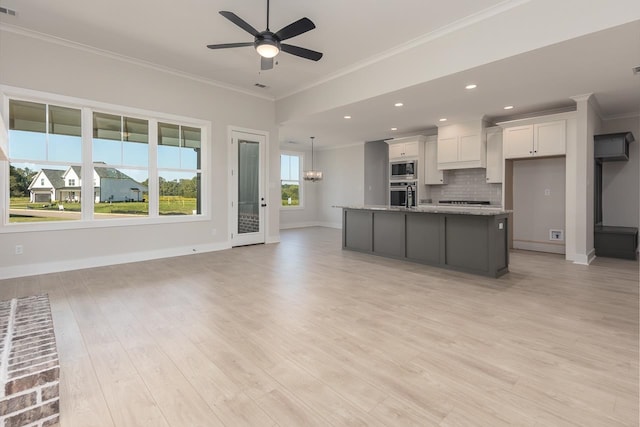 kitchen with white cabinetry, a kitchen island with sink, light stone countertops, and light hardwood / wood-style floors