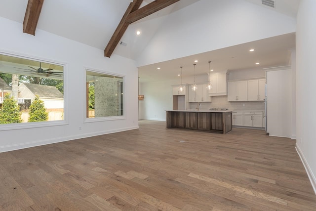 unfurnished living room with hardwood / wood-style floors, beam ceiling, and ceiling fan