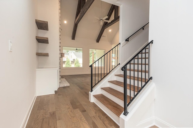 stairway featuring beam ceiling, ceiling fan, wood-type flooring, and high vaulted ceiling