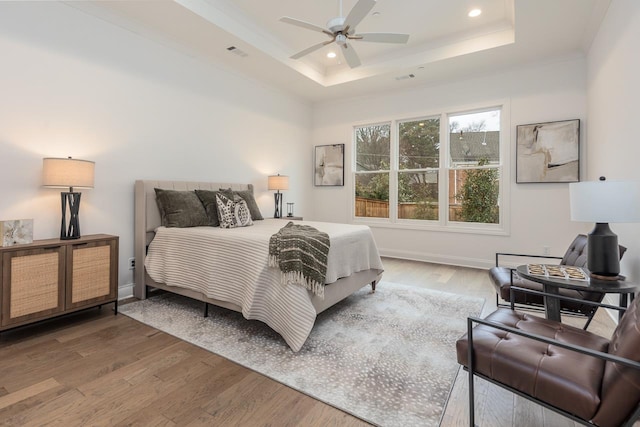 bedroom with ceiling fan, a raised ceiling, and hardwood / wood-style floors