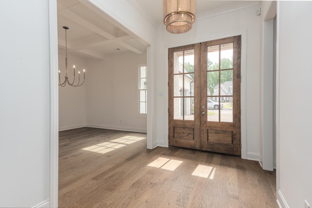 foyer entrance featuring beam ceiling, a notable chandelier, hardwood / wood-style flooring, and french doors