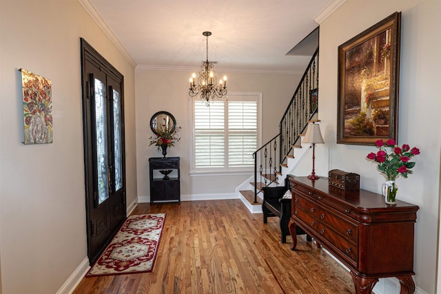 foyer with light hardwood / wood-style flooring, a notable chandelier, and ornamental molding