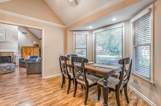 dining area featuring a wealth of natural light, a fireplace, lofted ceiling, and light wood-type flooring