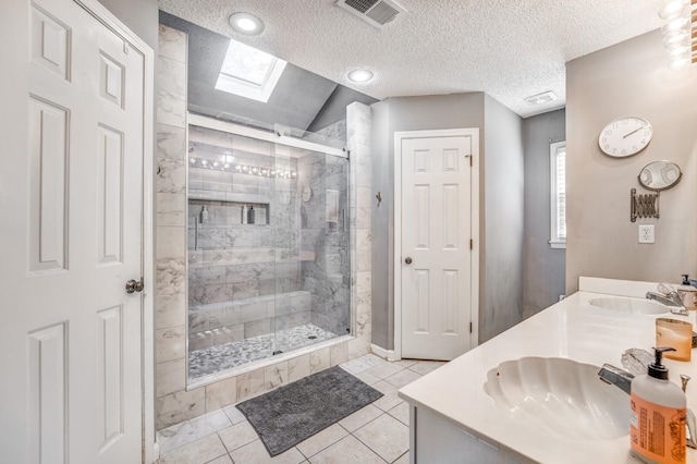 bathroom featuring tile patterned floors, vaulted ceiling with skylight, vanity, a textured ceiling, and a shower with shower door