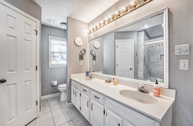 bathroom with a tile shower, tile patterned floors, a textured ceiling, toilet, and vanity