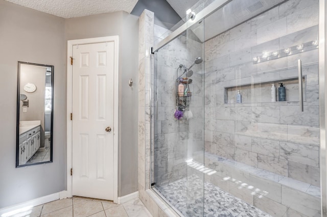 bathroom featuring vanity, a textured ceiling, a shower with shower door, and tile patterned flooring