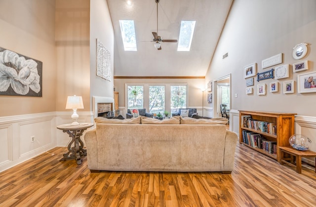 living room with wood-type flooring, a skylight, high vaulted ceiling, and ceiling fan