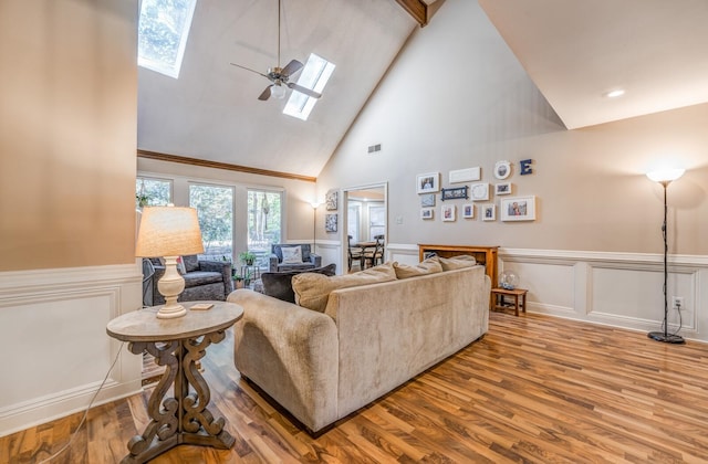 living room with hardwood / wood-style floors, a skylight, high vaulted ceiling, and ceiling fan