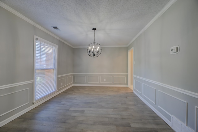 unfurnished dining area featuring wood-type flooring, an inviting chandelier, and crown molding