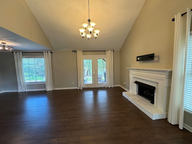 unfurnished living room with a chandelier, a brick fireplace, dark hardwood / wood-style flooring, and plenty of natural light