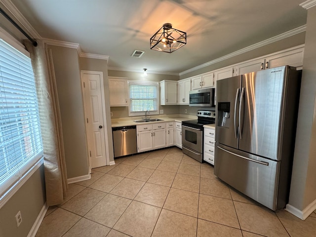 kitchen featuring ornamental molding, white cabinetry, sink, light tile patterned flooring, and appliances with stainless steel finishes