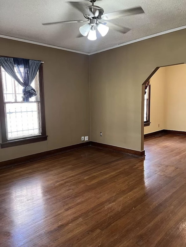 spare room featuring dark wood-type flooring, a textured ceiling, and crown molding