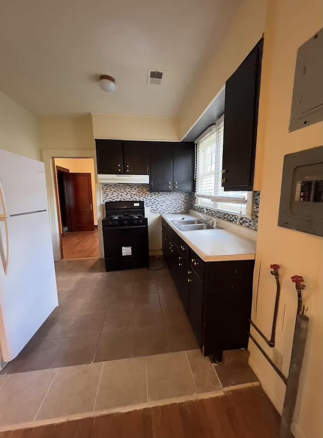 kitchen with tile patterned flooring, sink, electric panel, black range with gas cooktop, and white fridge