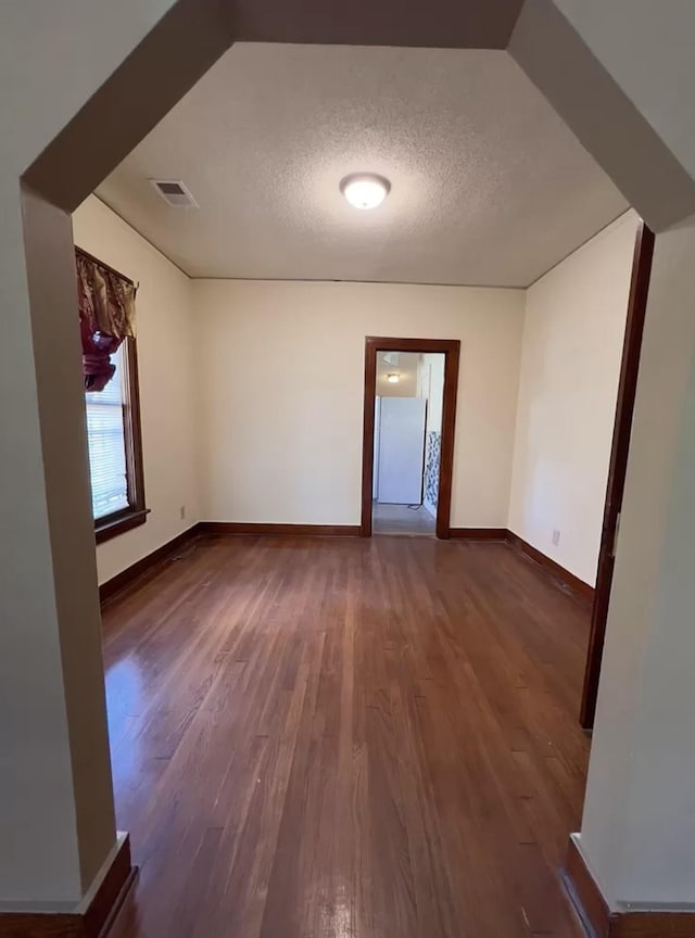 spare room featuring dark wood-type flooring and a textured ceiling