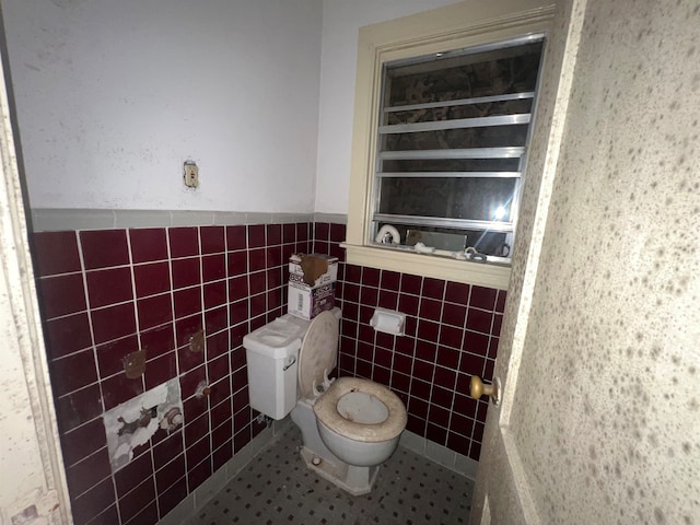 bathroom featuring tile patterned flooring, tile walls, and toilet