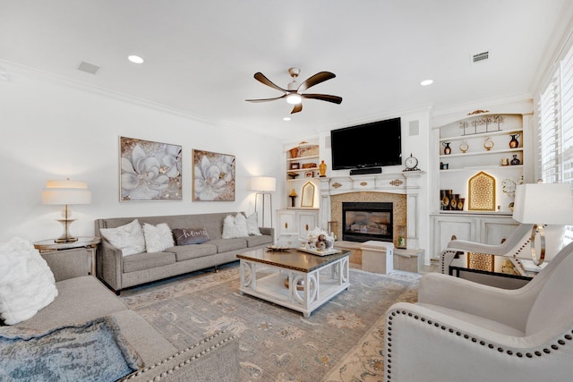 living room featuring built in shelves, ceiling fan, and ornamental molding