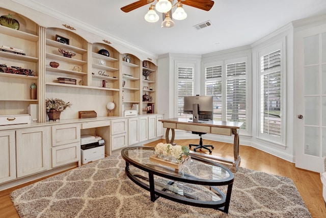 home office featuring light wood-type flooring, built in features, ceiling fan, and crown molding