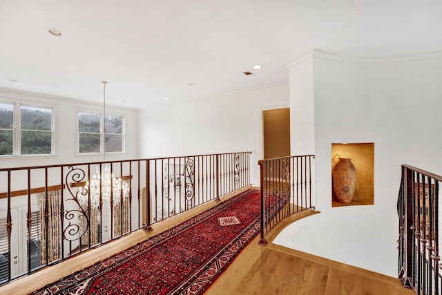 hallway with a chandelier, wood-type flooring, and crown molding