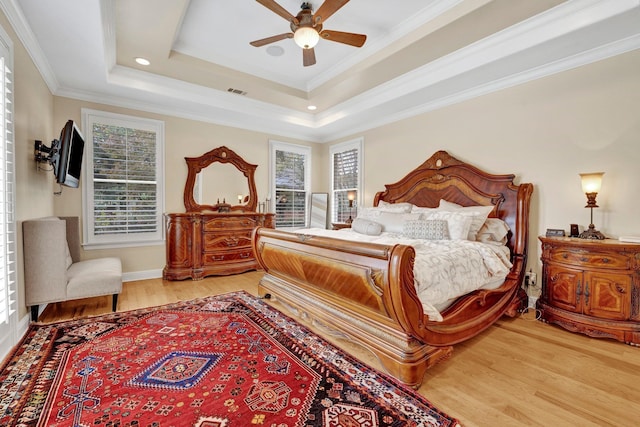 bedroom featuring a raised ceiling, ceiling fan, crown molding, and wood-type flooring