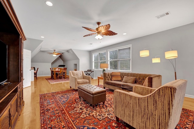 living room with ceiling fan, light hardwood / wood-style floors, and lofted ceiling