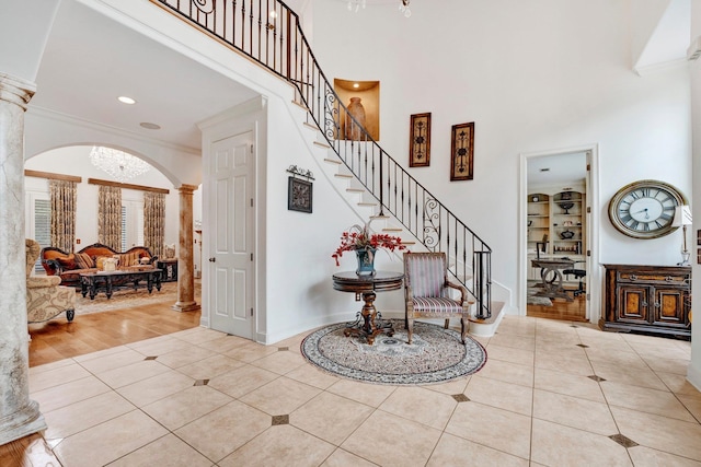 foyer entrance featuring ornate columns, ornamental molding, and light hardwood / wood-style flooring