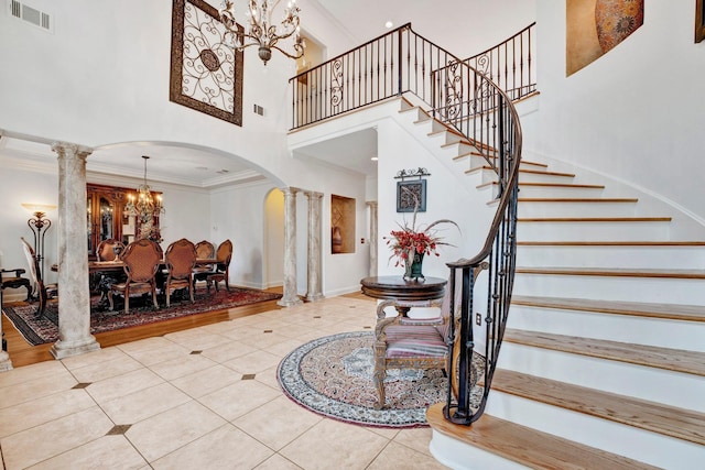 entrance foyer featuring decorative columns, tile patterned floors, crown molding, and a high ceiling