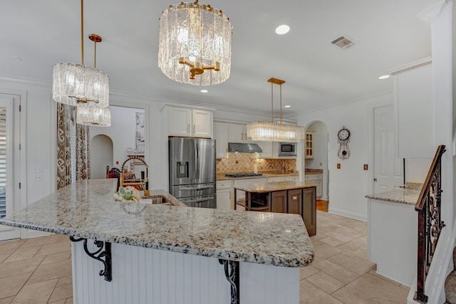 kitchen with appliances with stainless steel finishes, ventilation hood, pendant lighting, white cabinets, and a large island