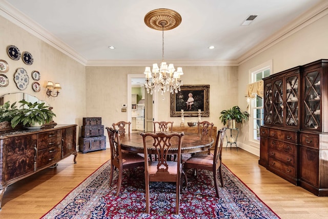 dining area with crown molding, a chandelier, and light wood-type flooring