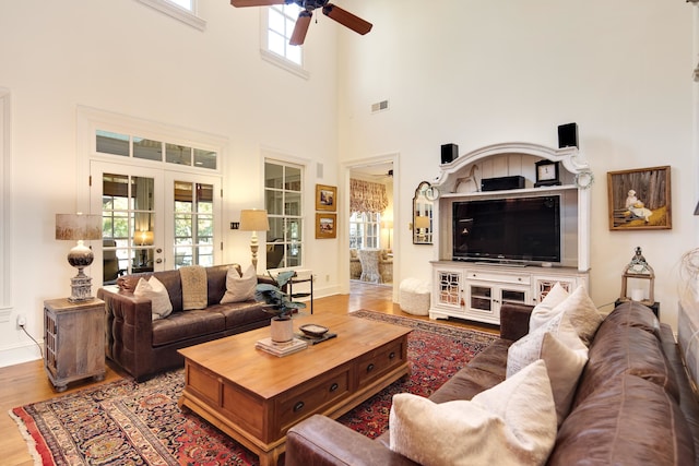 living room with hardwood / wood-style floors, a wealth of natural light, a high ceiling, and ceiling fan