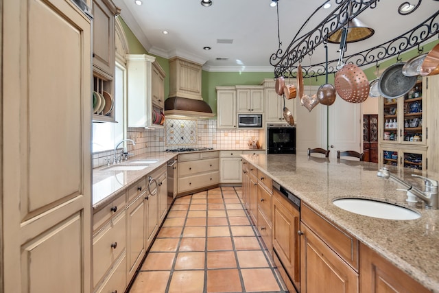 kitchen featuring custom exhaust hood, light stone counters, sink, and appliances with stainless steel finishes