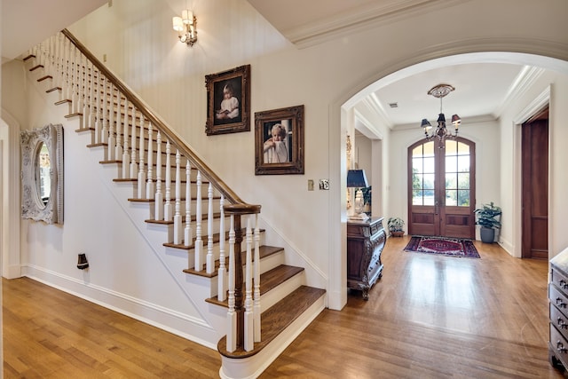 entrance foyer featuring hardwood / wood-style floors, a notable chandelier, ornamental molding, and french doors