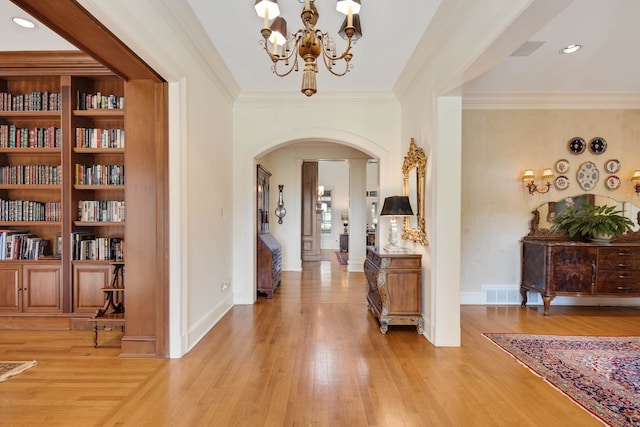 entrance foyer with light hardwood / wood-style floors, an inviting chandelier, and crown molding