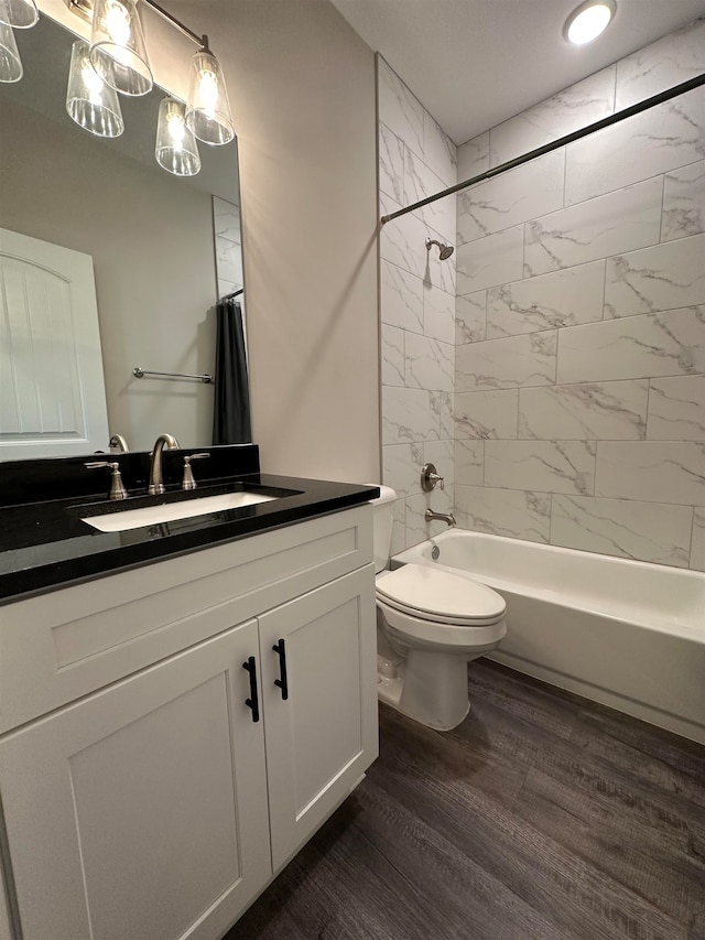 full bathroom with vanity, wood-type flooring, tiled shower / bath combo, and toilet