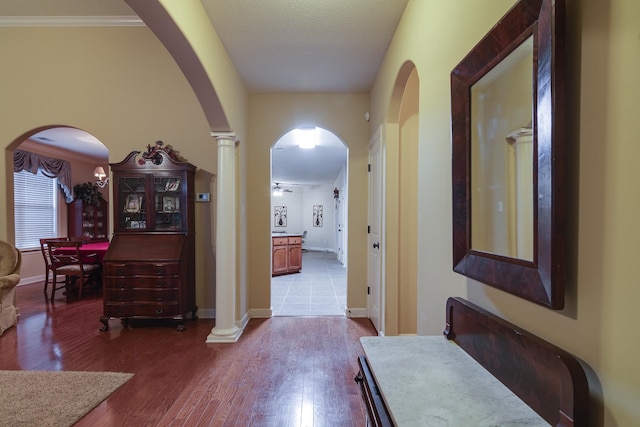 hall featuring hardwood / wood-style floors, ornate columns, and ornamental molding