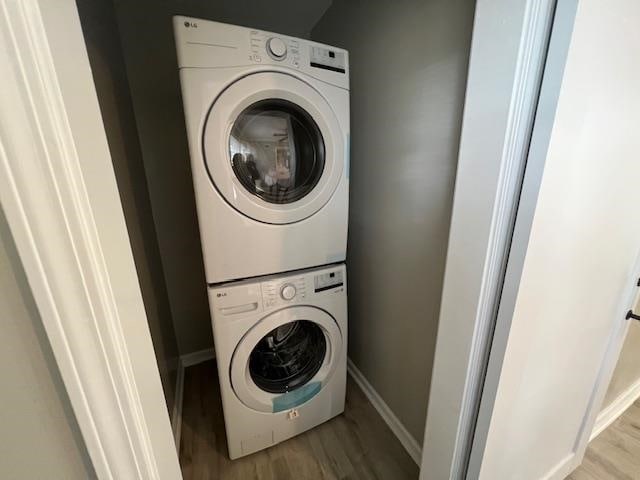 clothes washing area featuring stacked washer and dryer and light hardwood / wood-style floors