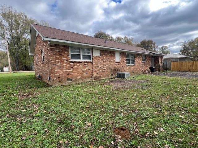 back of house with central AC unit and a yard