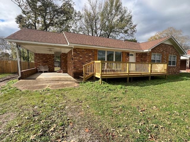 rear view of house featuring a yard, a deck, and ceiling fan