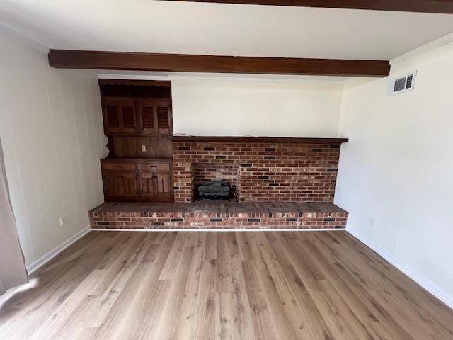 unfurnished living room featuring wood-type flooring, ornamental molding, and beam ceiling