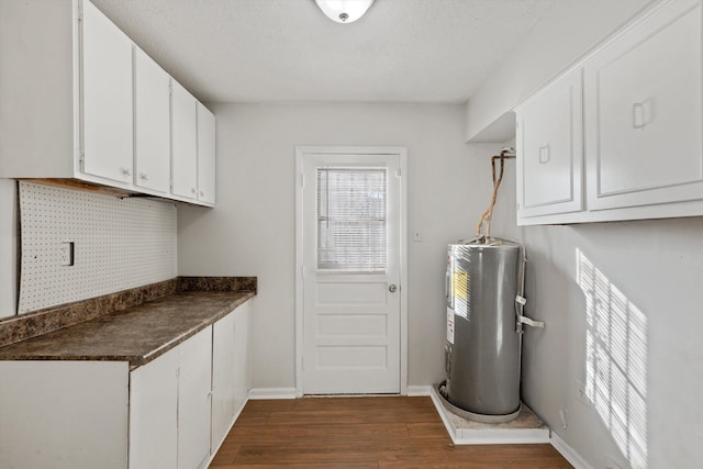 interior space featuring white cabinetry, electric water heater, dark hardwood / wood-style floors, backsplash, and a textured ceiling