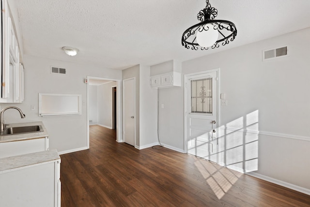 unfurnished dining area featuring a textured ceiling, dark hardwood / wood-style floors, and sink