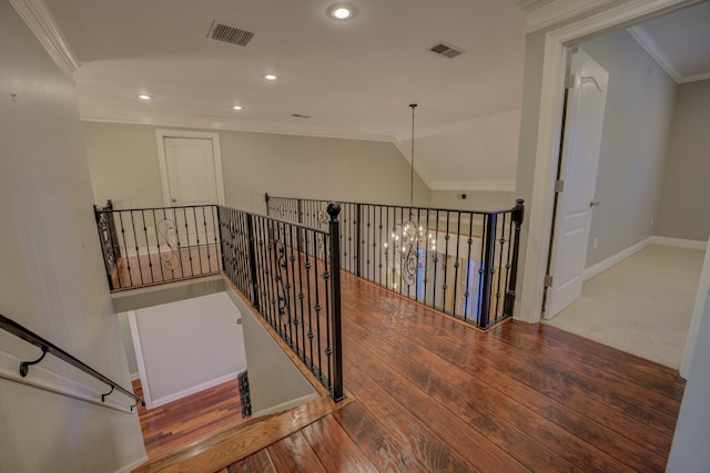 stairway featuring vaulted ceiling, wood-type flooring, crown molding, and a chandelier